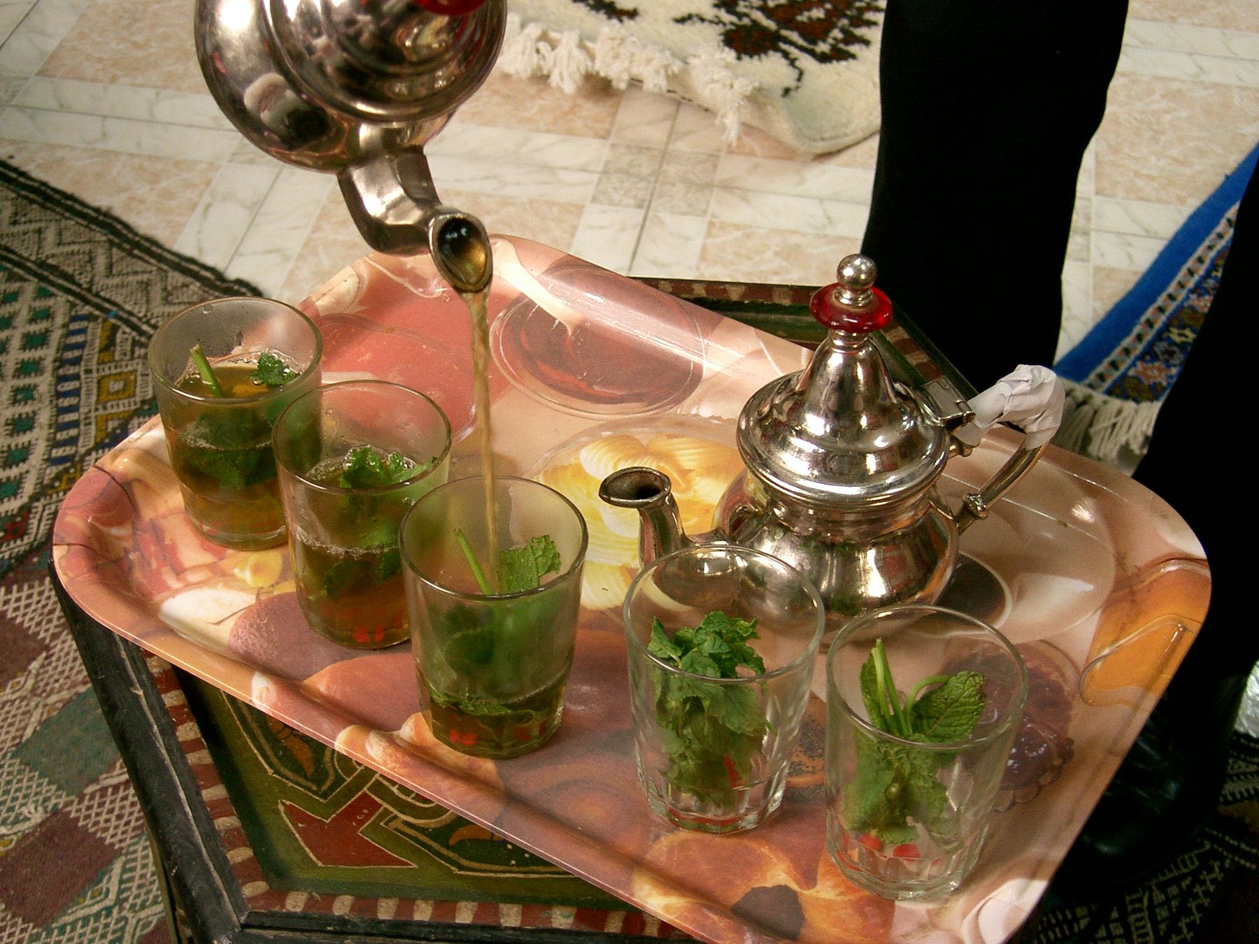 Mint tea being poured into glasses on a tray in Tangier